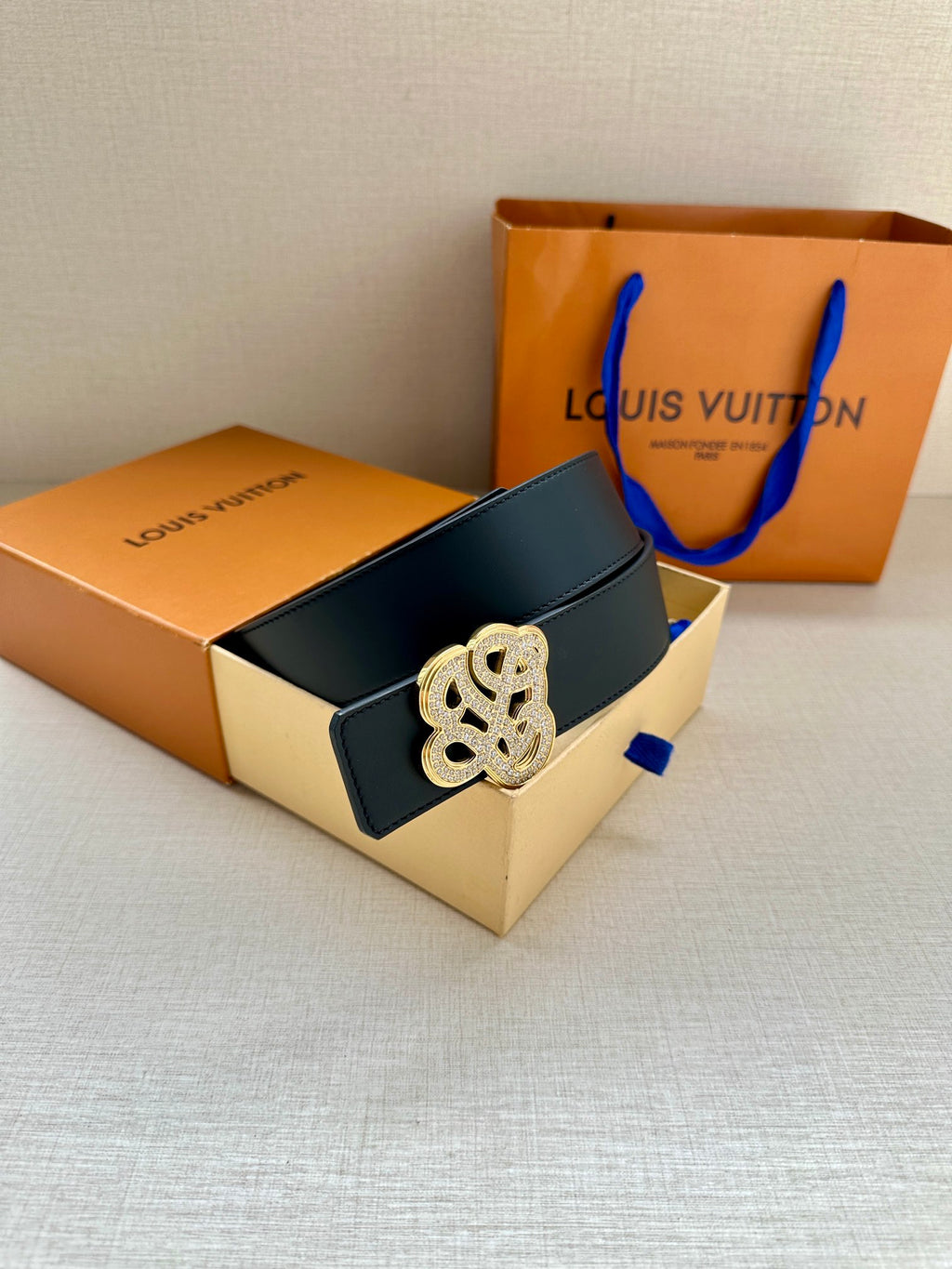 Dark blue leather belt with silver-tone monogram buckle and adjustable end.