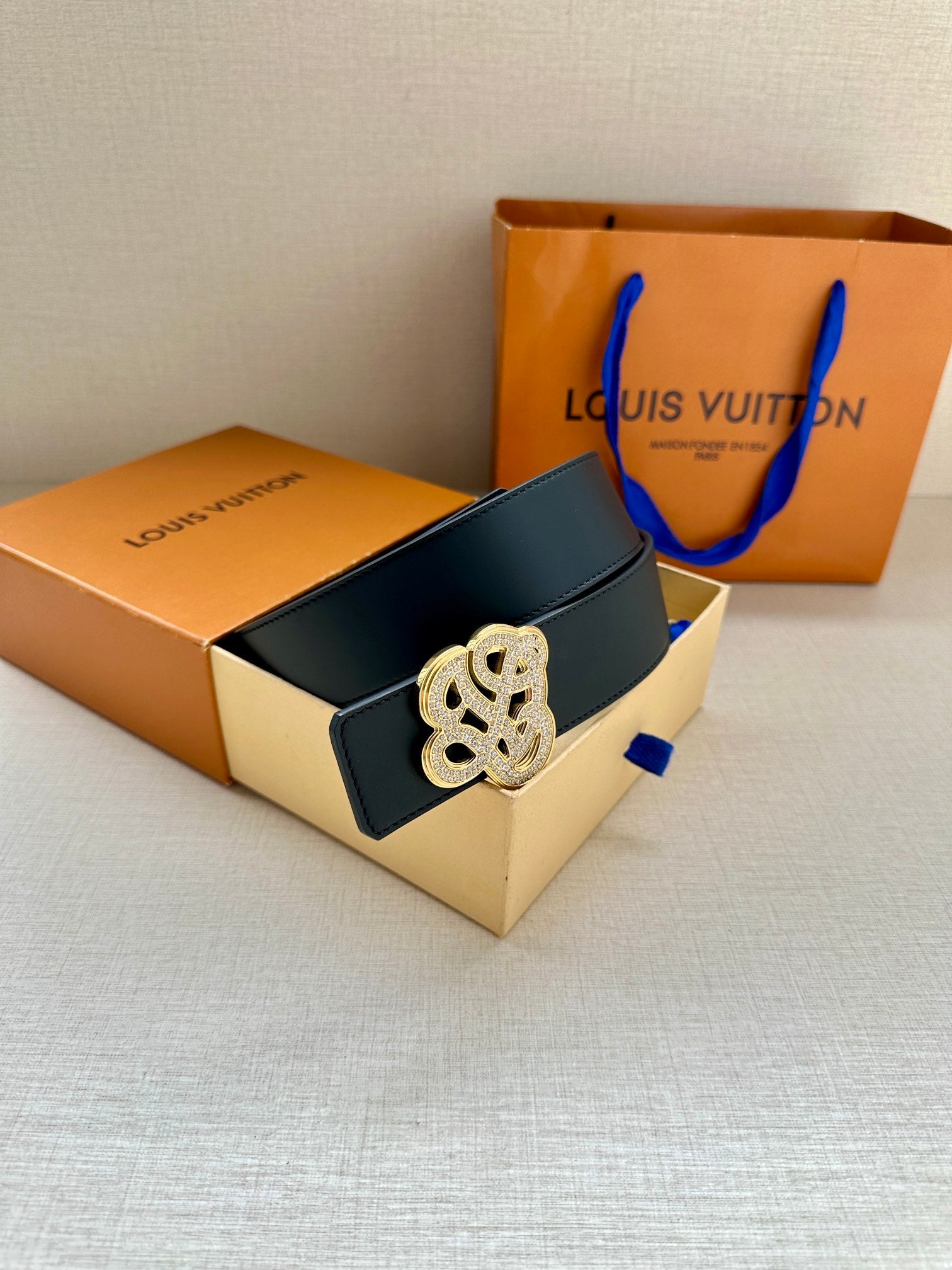 Dark blue leather belt with silver-tone monogram buckle and adjustable end.