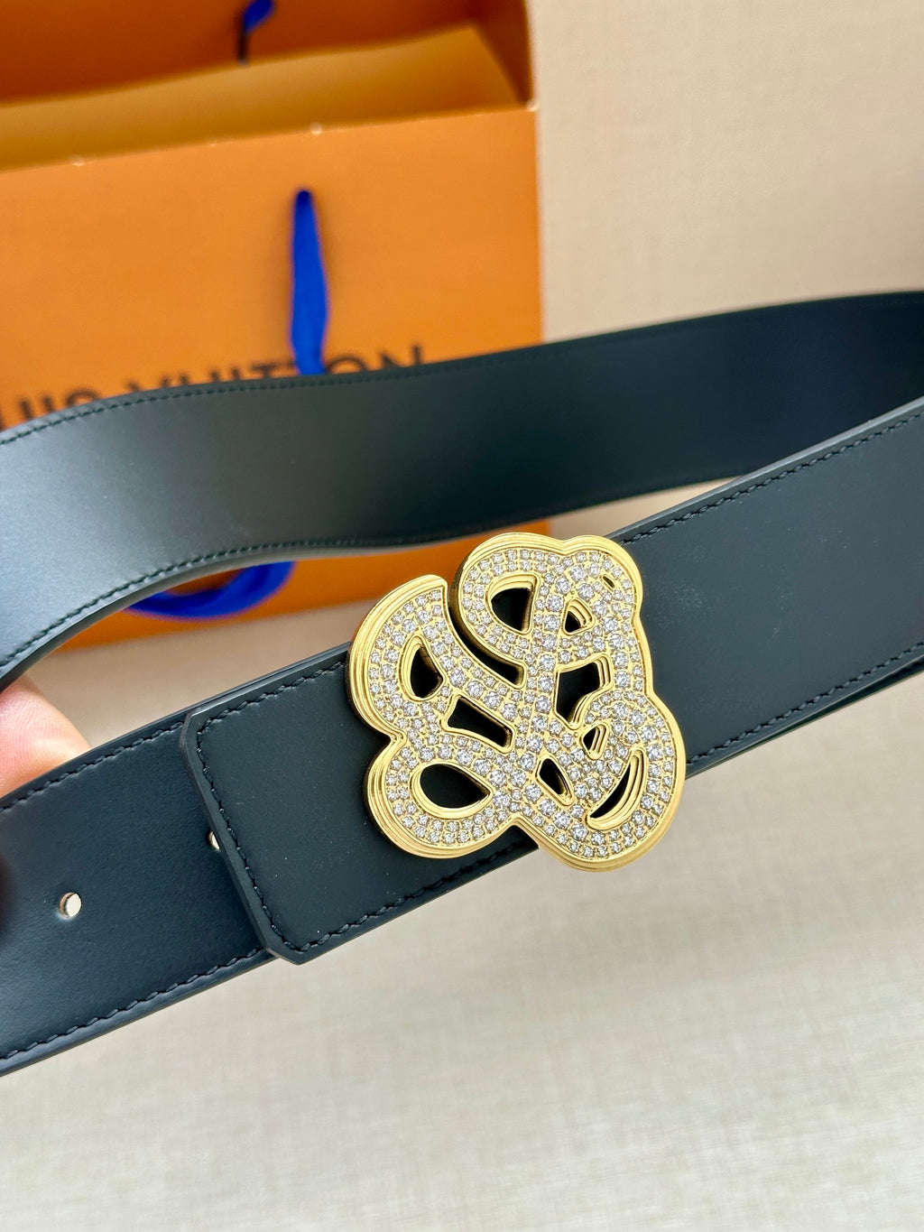 Dark blue leather belt with silver-tone monogram buckle detail.