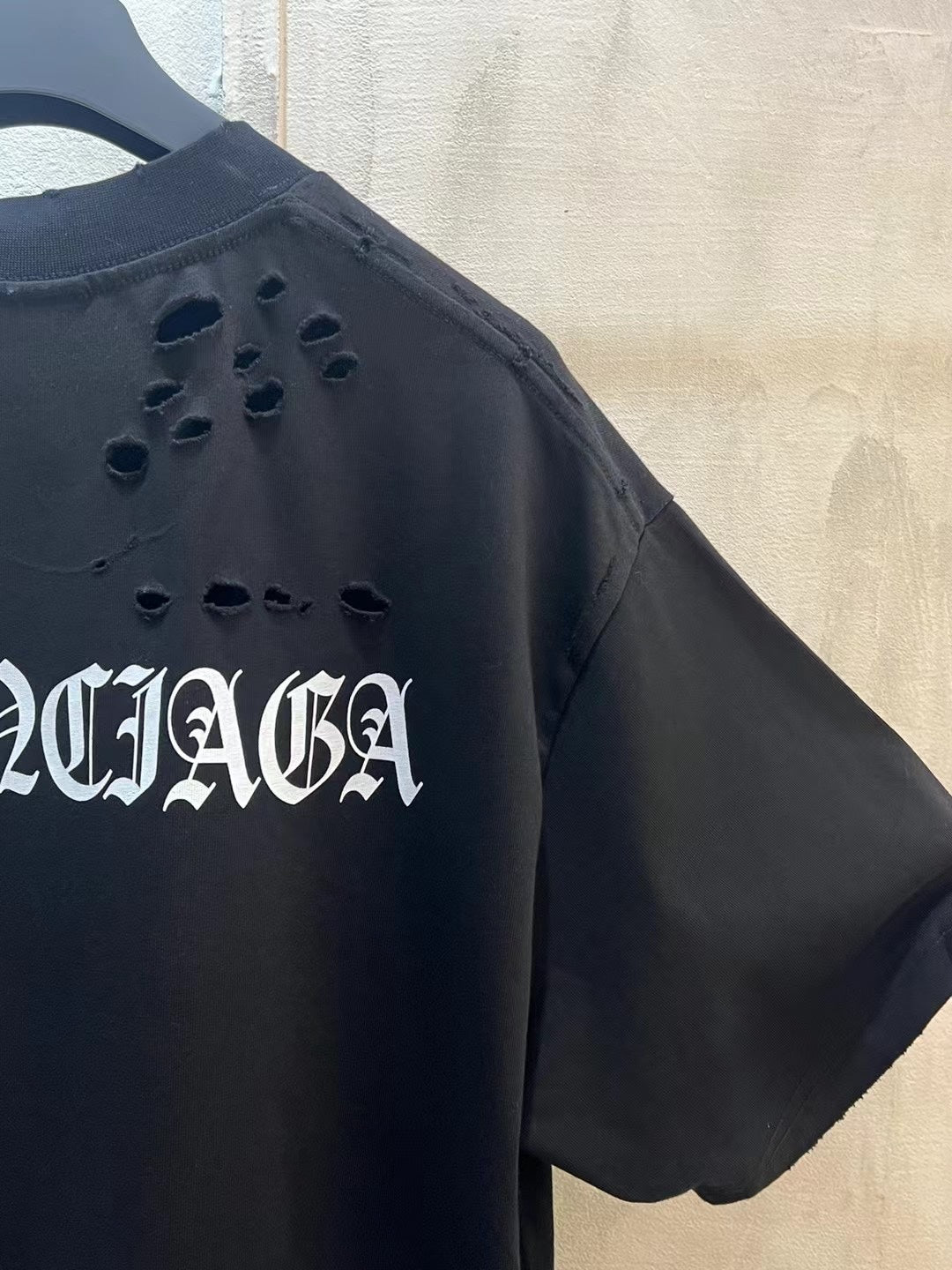 Black T-shirt sleeve detail with BALENCIAGA cutout lettering