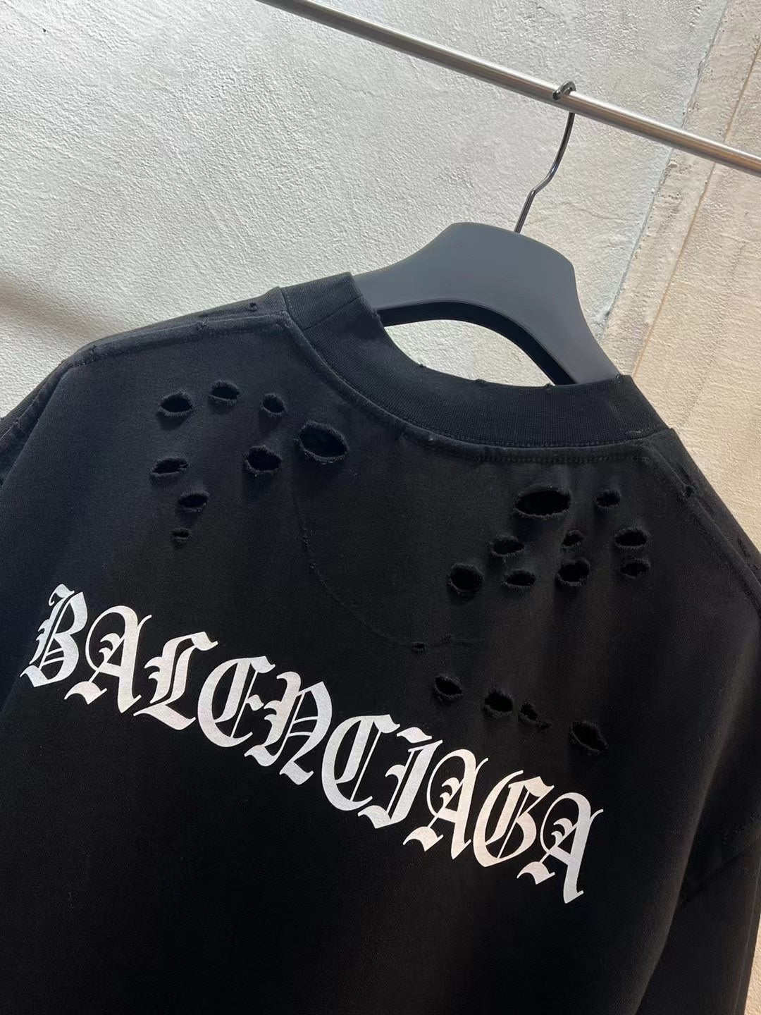 Black crewneck T-shirt close-up: BALENCIAGA cutout letters across chest
