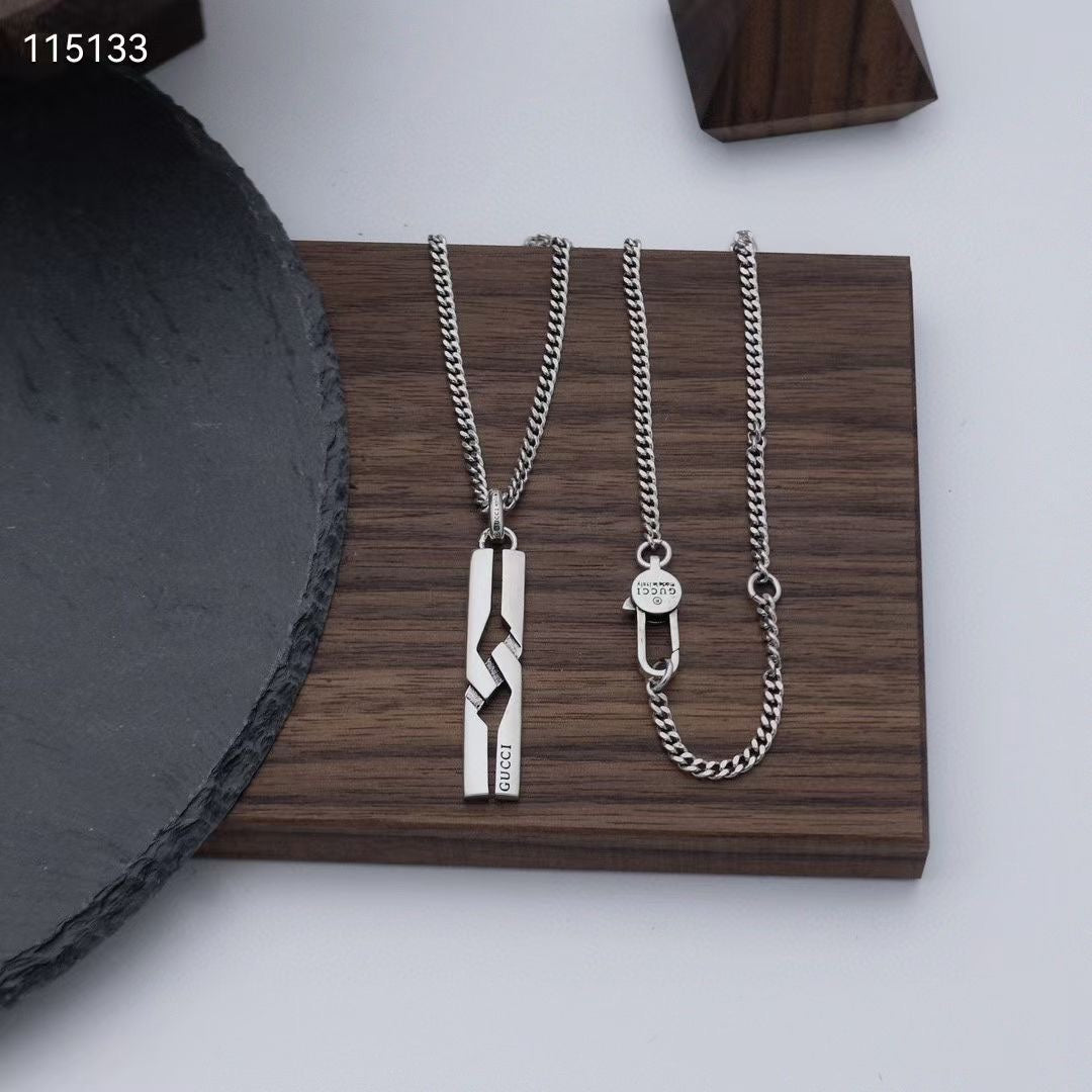 Set of silver-tone necklaces on tray: rectangular pendant, round tag, chain