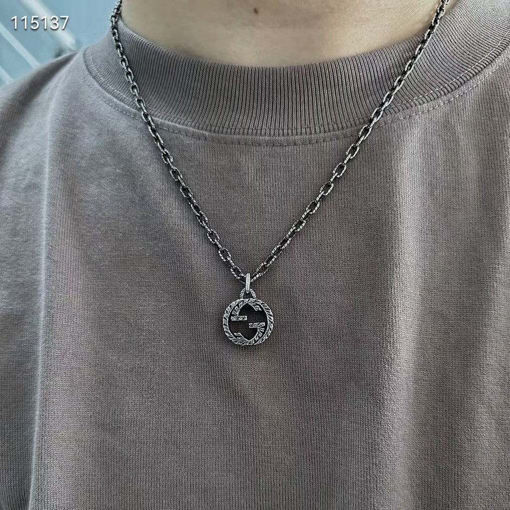 Gucci silver-tone round logo pendant necklace worn on a crewneck shirt