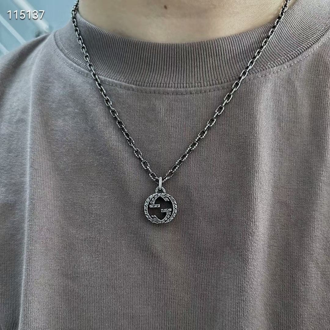 Gucci silver-tone round logo pendant necklace worn on a crewneck shirt