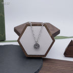 Gucci silver-tone round logo pendant necklace on a white display stand