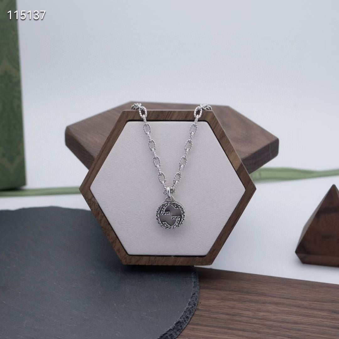 Gucci silver-tone round logo pendant necklace on a white display stand