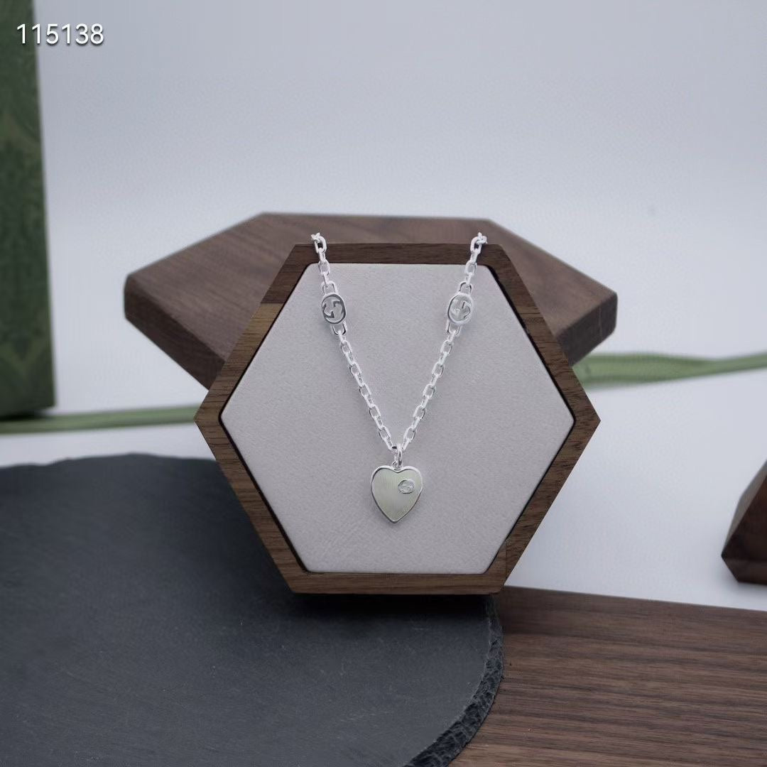 Gucci silver heart pendant necklace on a hexagon jewelry display stand
