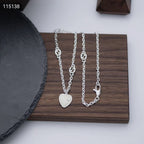 Gucci silver heart pendant necklace set on a wooden tray, close-up view