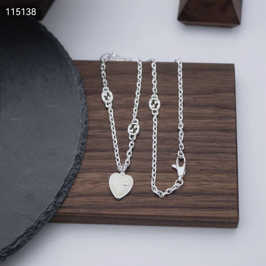 Gucci silver heart pendant necklace set on a wooden tray, close-up view