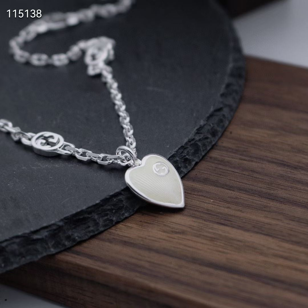Gucci silver heart pendant necklace with engraved charm on wooden surface