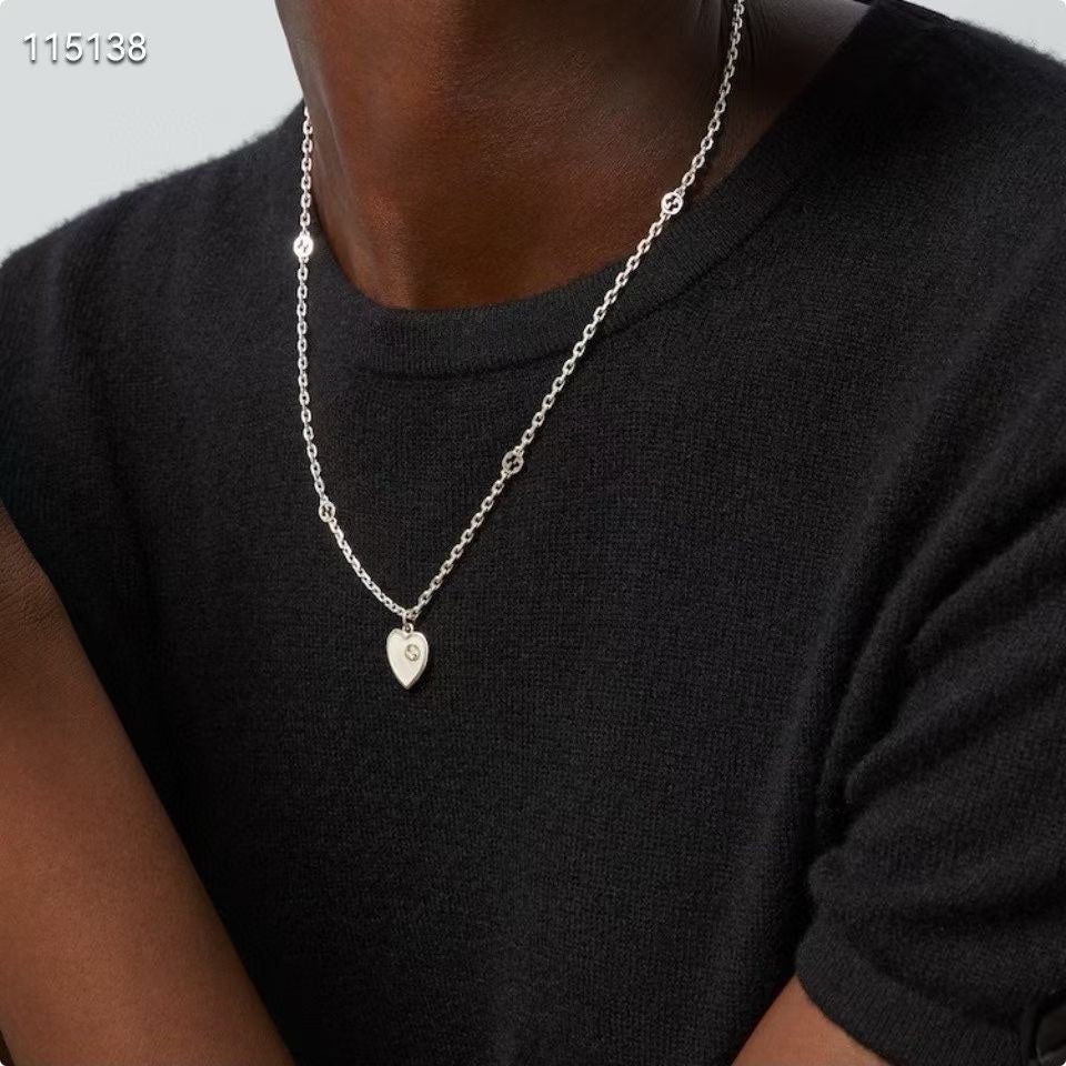 Gucci silver heart pendant necklace worn with a black top, pendant centered