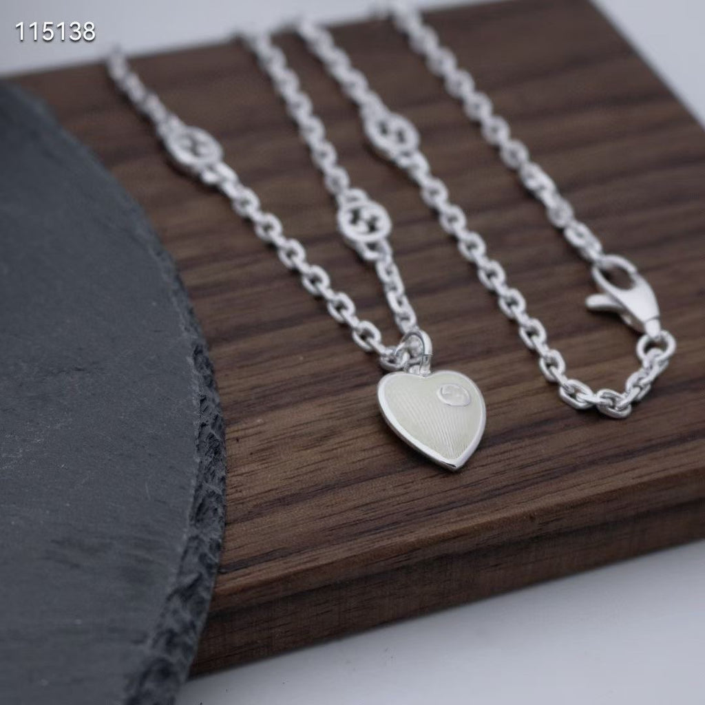 Gucci silver heart pendant necklace, heart charm detail on wooden board close-up