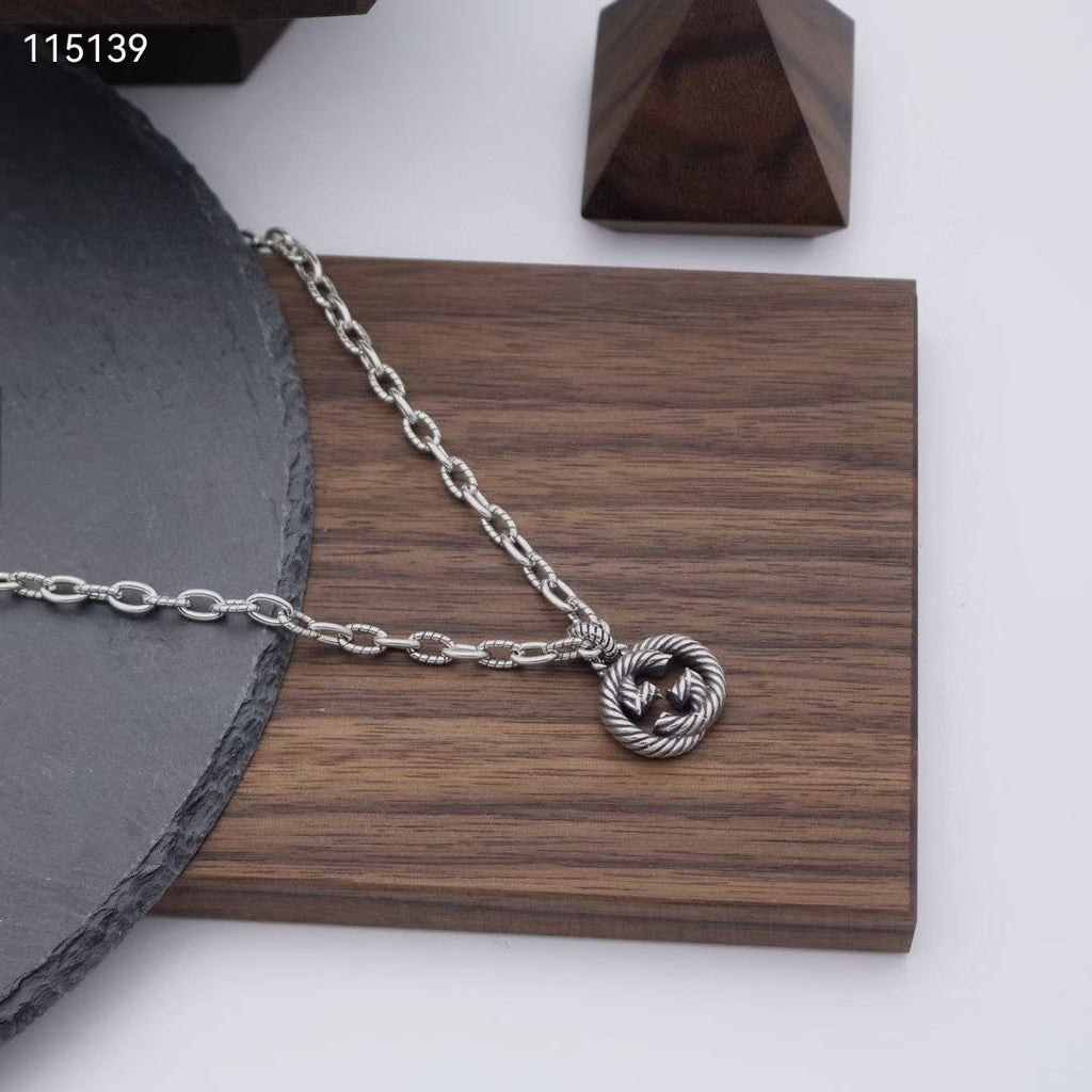 Silver-tone chain necklace with round knot pendant on a wooden display board