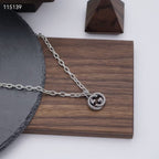 Silver-tone chain necklace with round knot pendant on a wooden display board