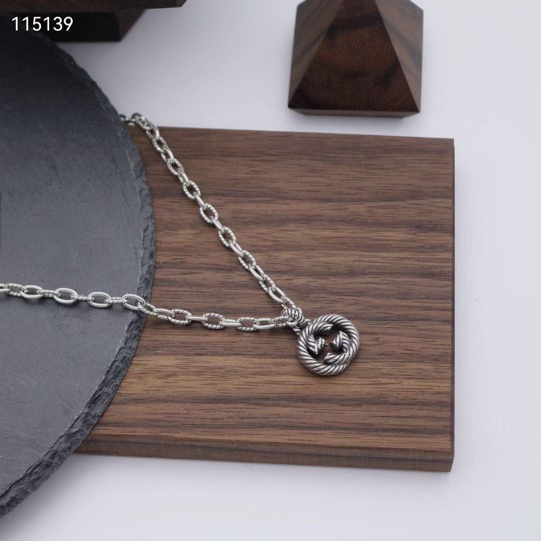 Silver-tone chain necklace with round knot pendant on a wooden display board