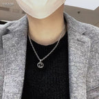 Silver-tone chain necklace with round knot pendant, worn with a dark knit top