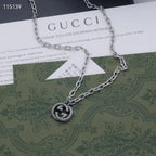 Silver-tone chain necklace with round knot pendant, laid over a green card