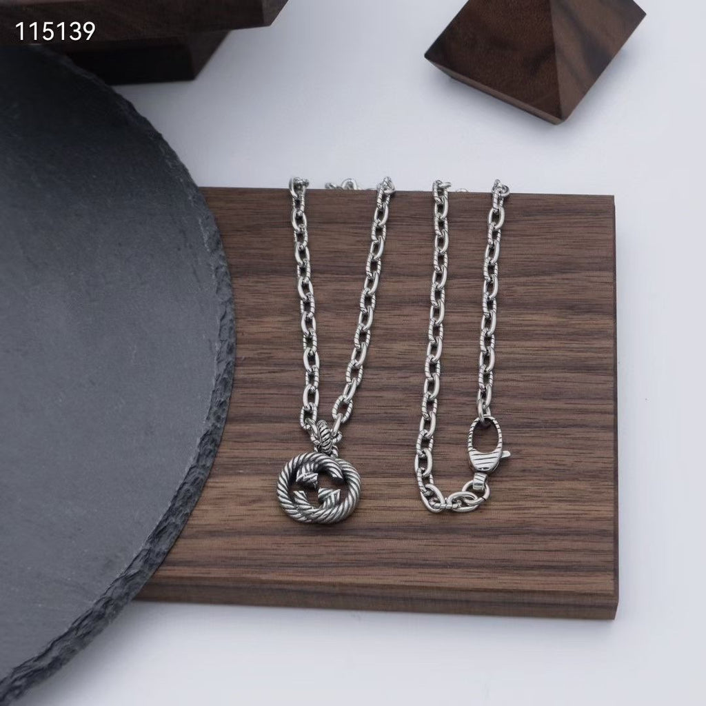 Four silver-tone chain necklaces with round knot pendants, displayed on a board