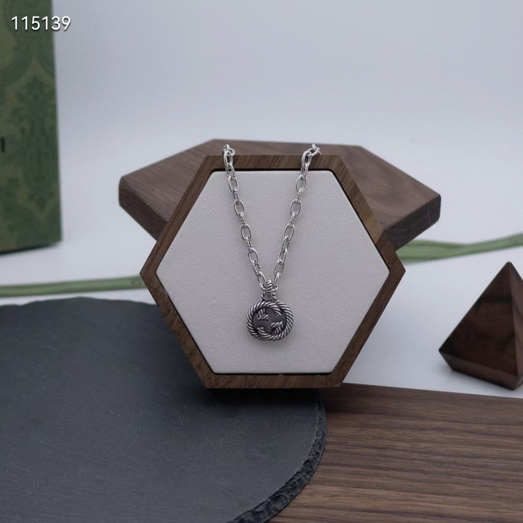 Silver-tone chain necklace with round knot pendant on a hexagonal jewelry stand