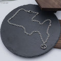 Silver-tone chain necklace with round knot pendant, lobster clasp visible