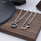 Silver-tone chain necklaces with round knot pendants and lobster clasps, on display