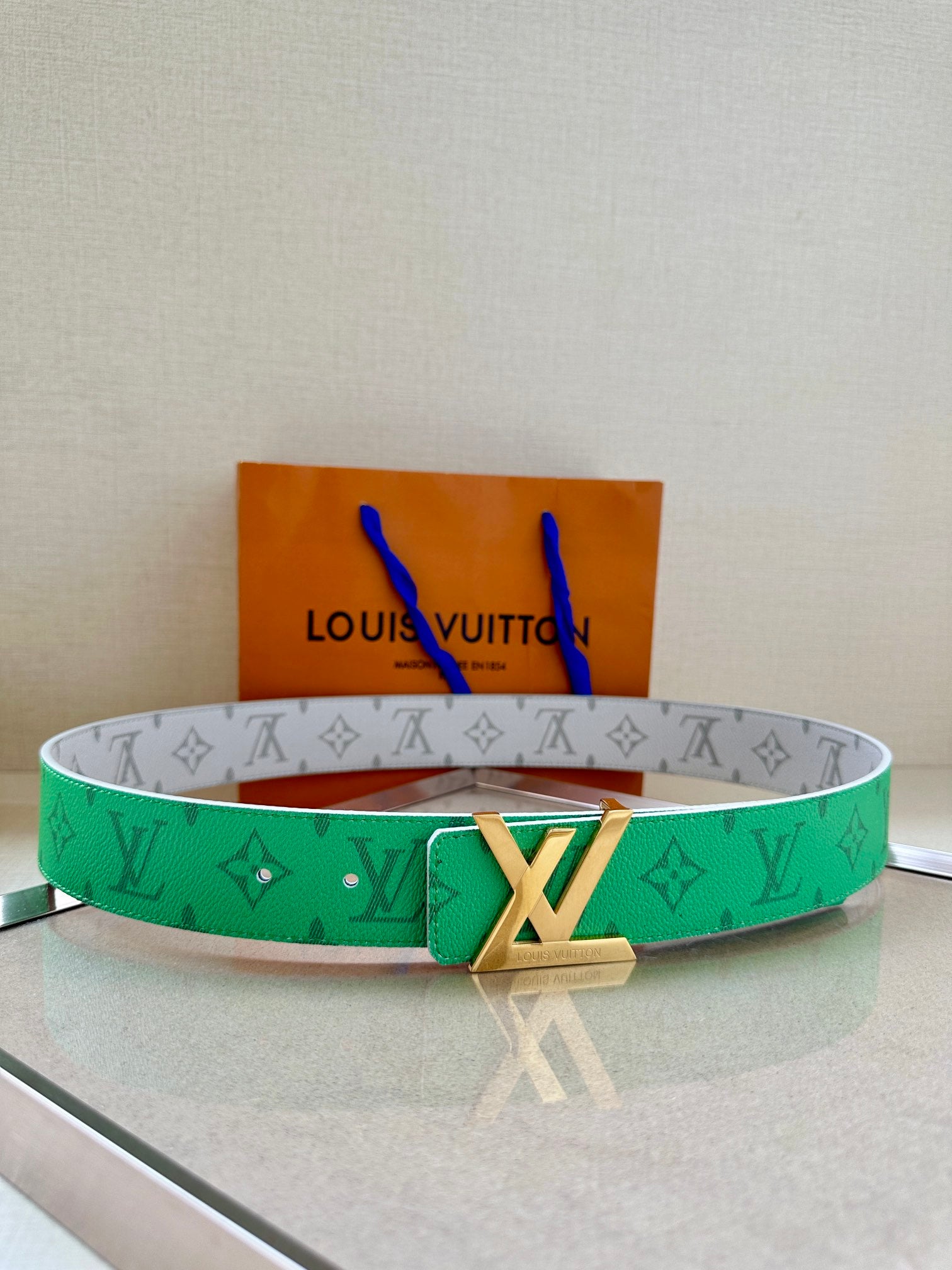 Green-and-gray patterned belt with gold buckle and LV monogram detail