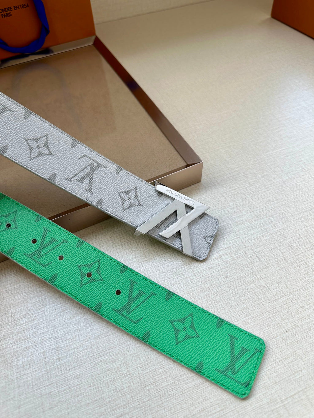 Green leather belt with LV pattern, visible rows of adjustment holes
