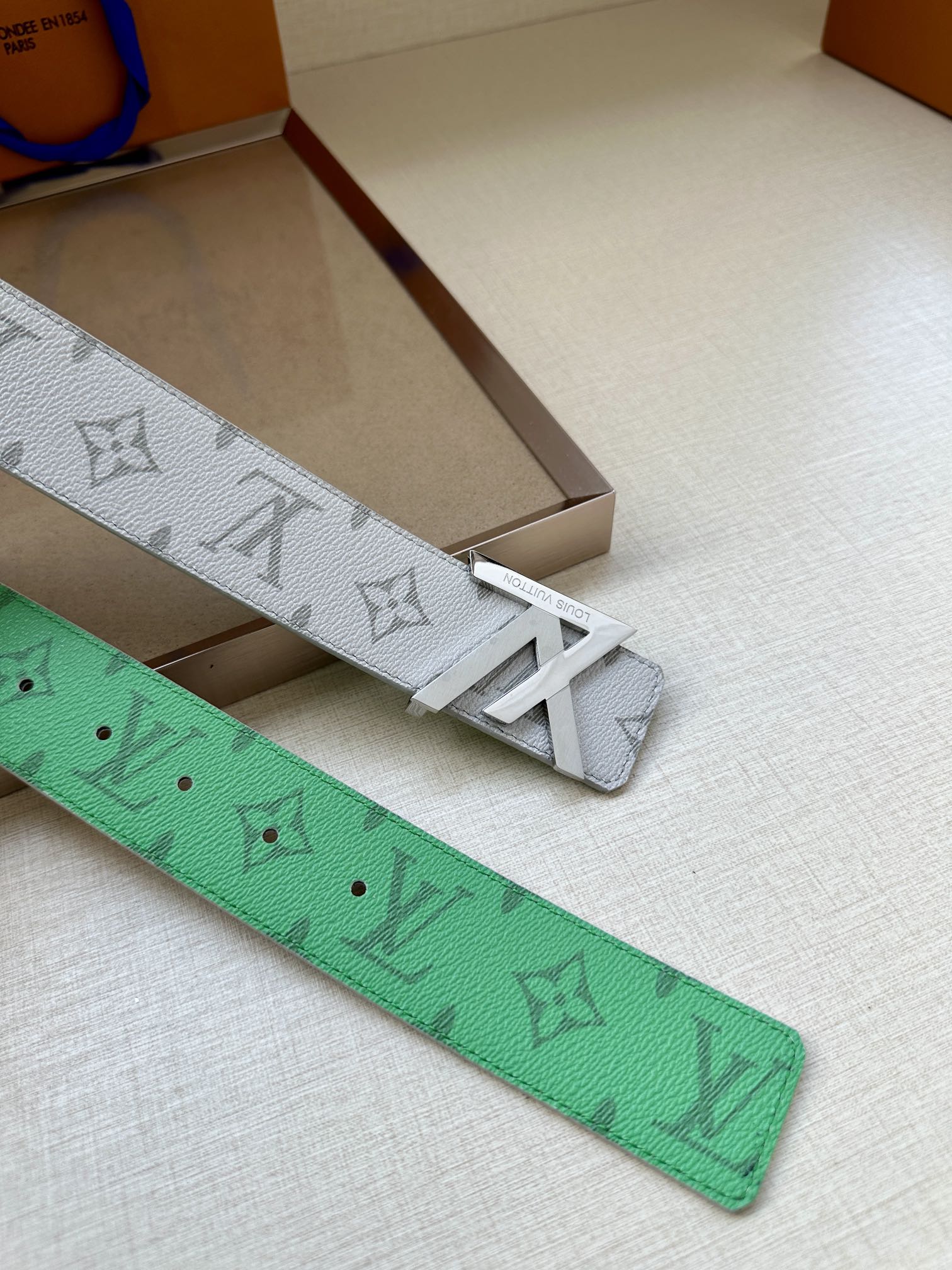 Green leather belt with LV pattern, visible rows of adjustment holes