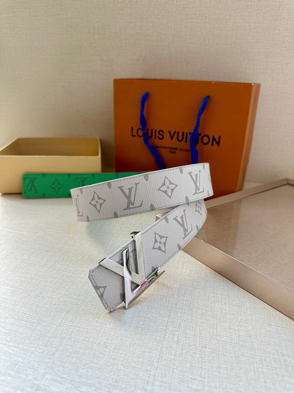 White monogram belt with green lining and gold buckle, side view