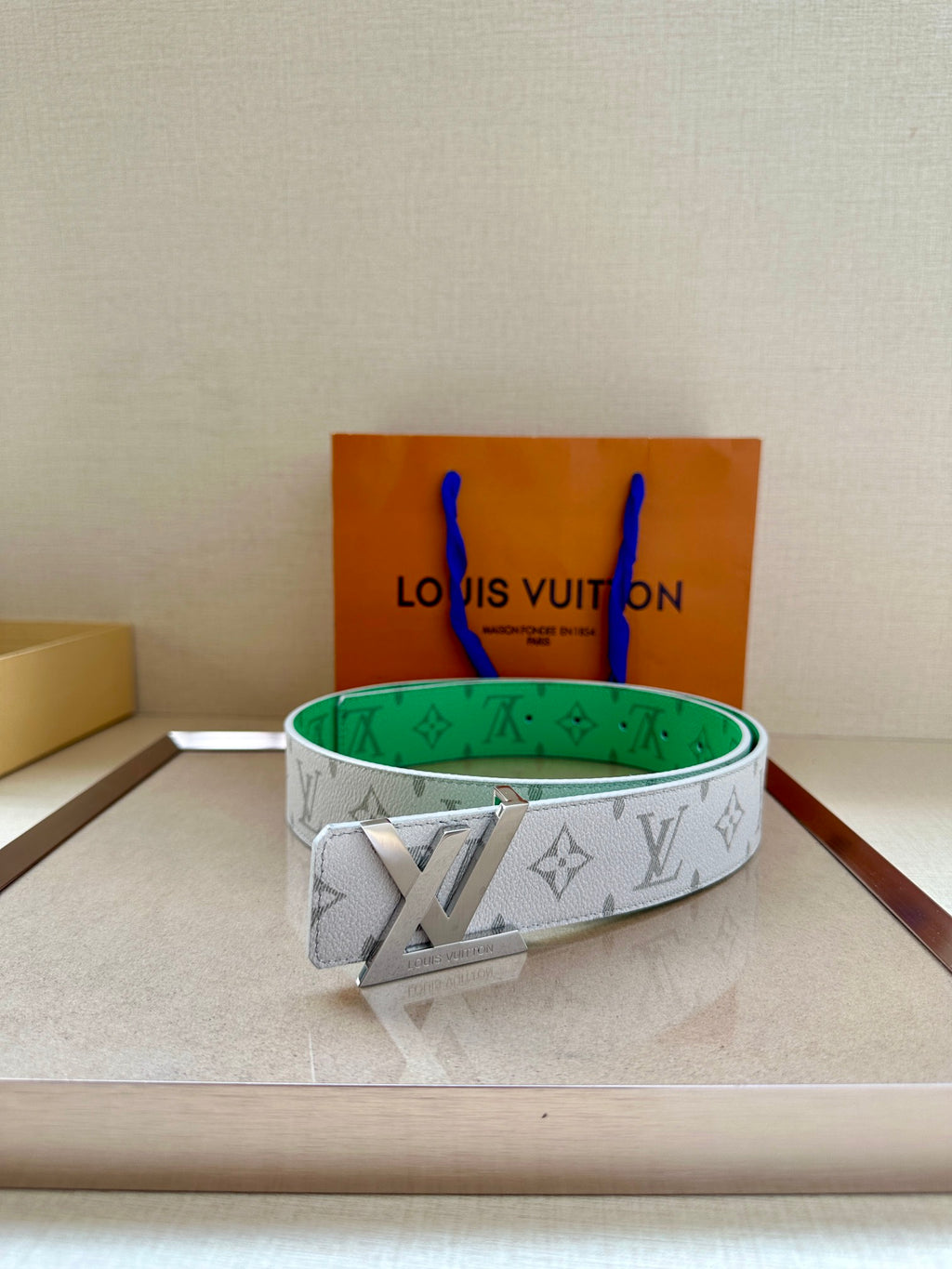 White monogram belt with green underside and gold buckle