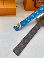 Blue and brown monogram belts with gold-toned buckles, laid on a tray