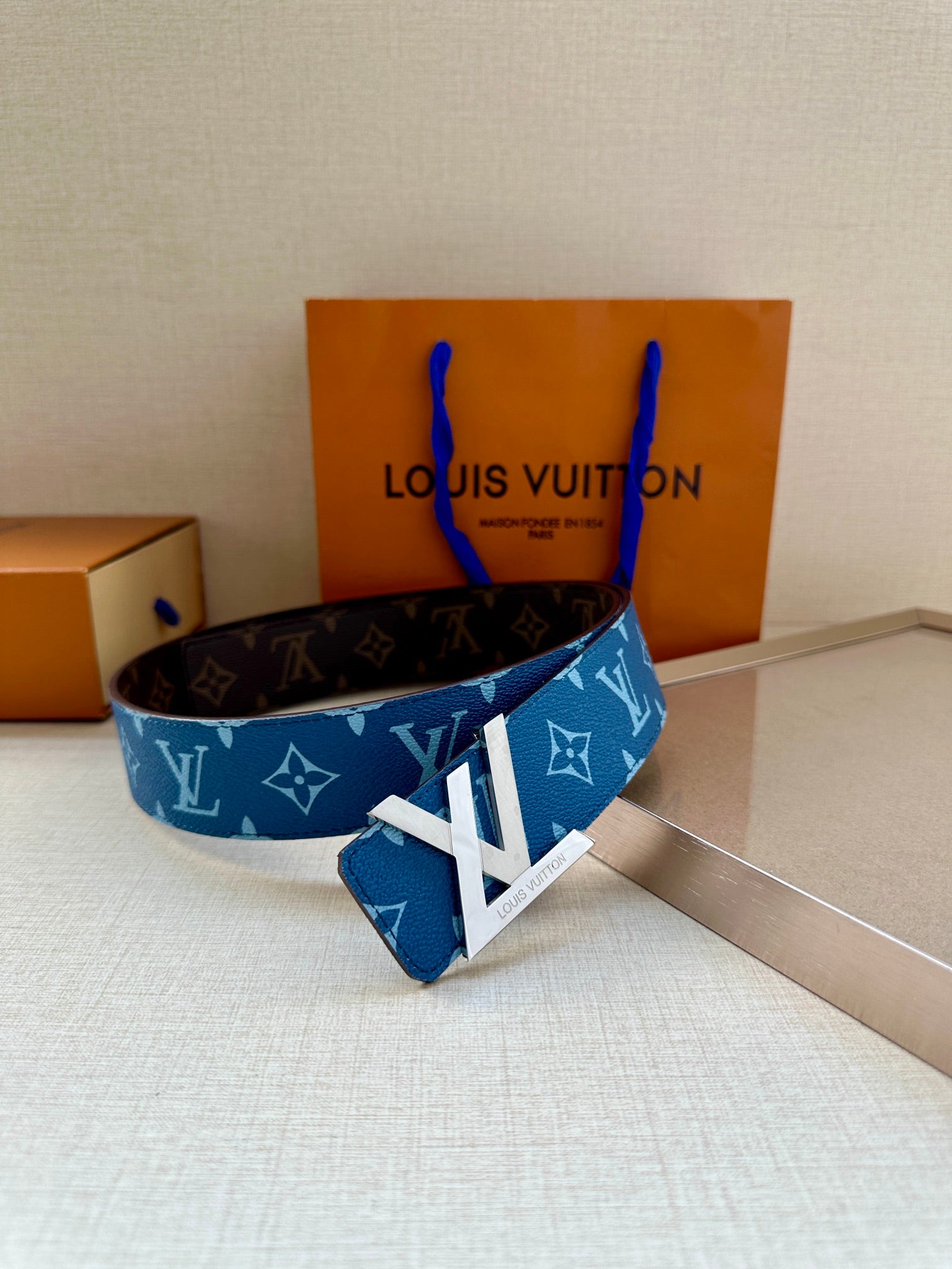 Blue monogram belt with gold-toned LV buckle, shown alongside dark belt