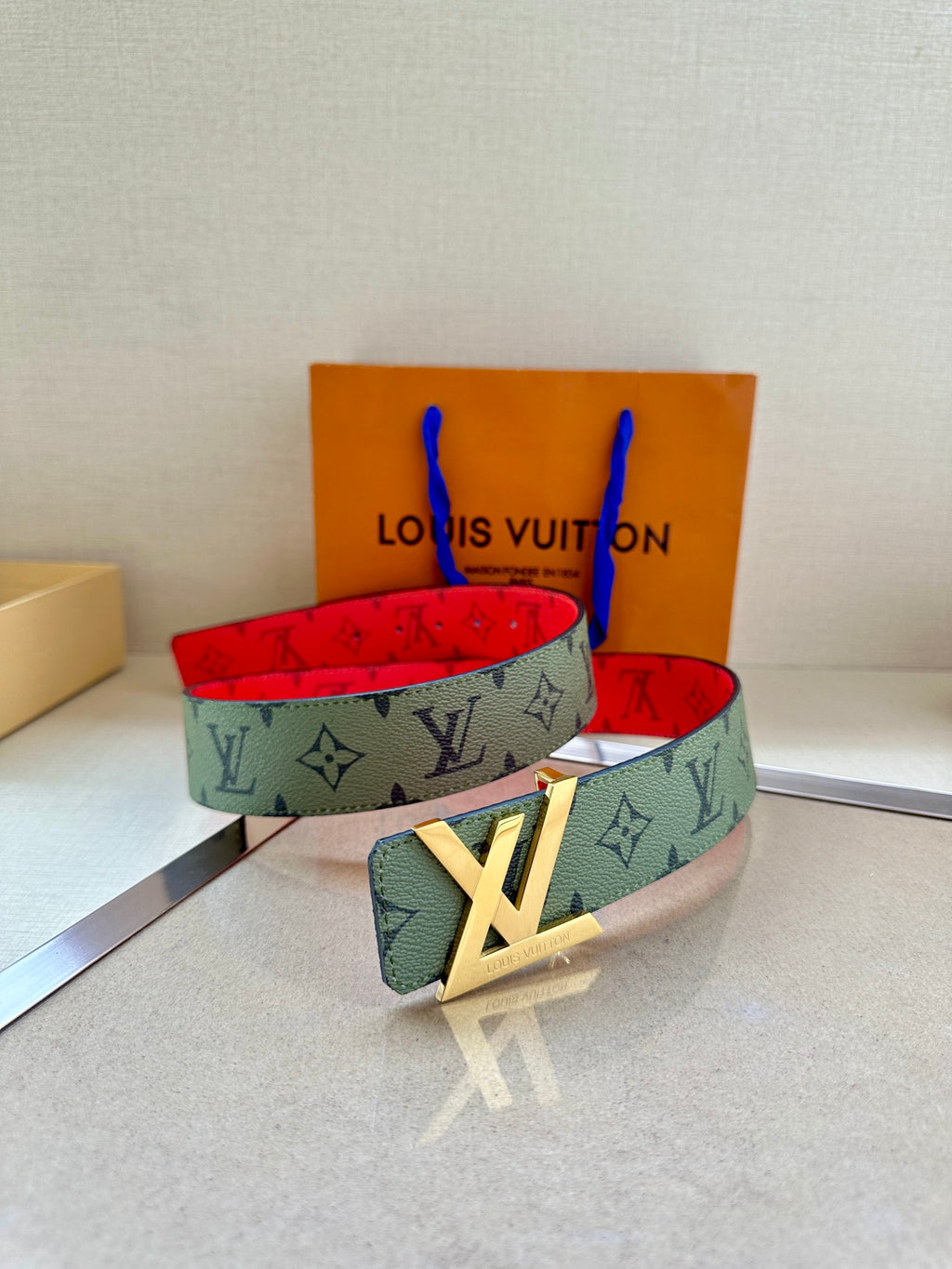 Two-tone monogram belt set: green-gray strap with red interior and gold buckle