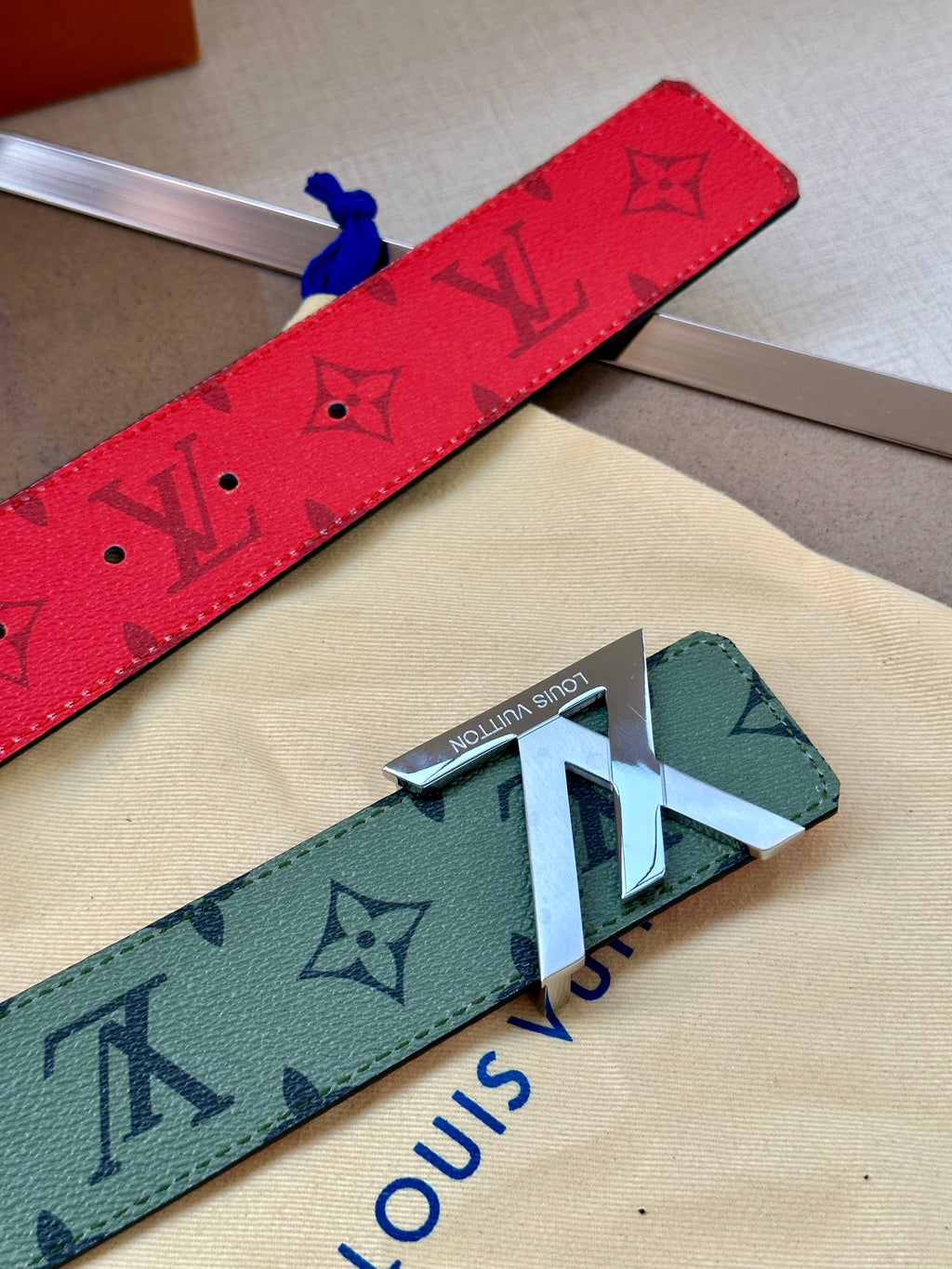 Red and green-gray monogram belts with metal buckle and LV-style motifs