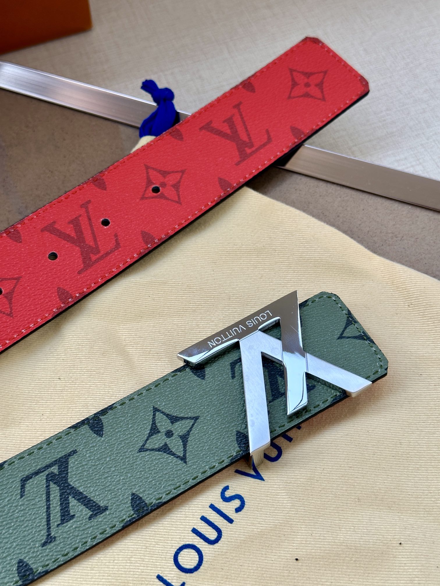 Red and green-gray monogram belts with metal buckle and LV-style motifs