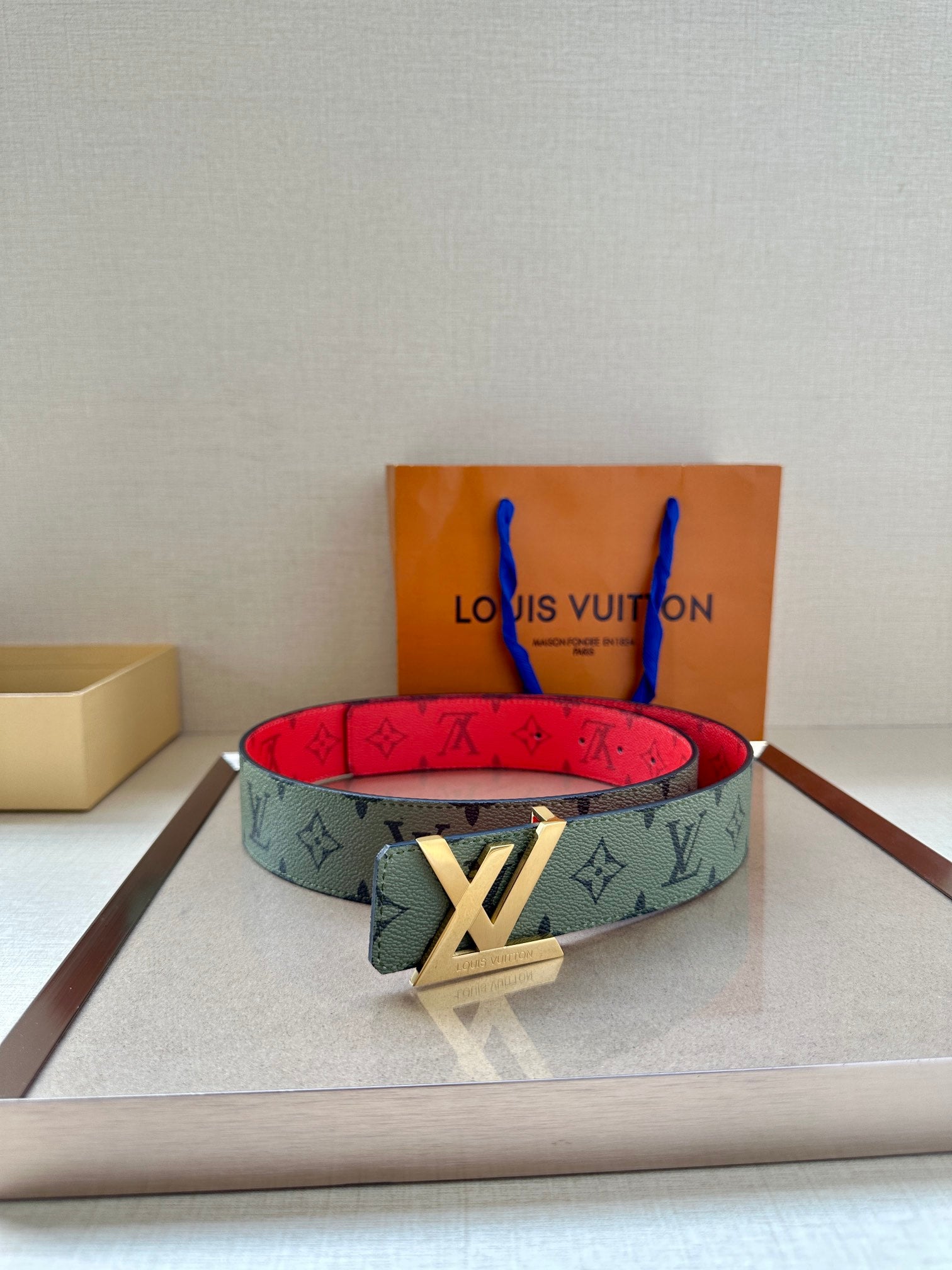Green-gray monogram belt with red underside and gold-tone LV buckle