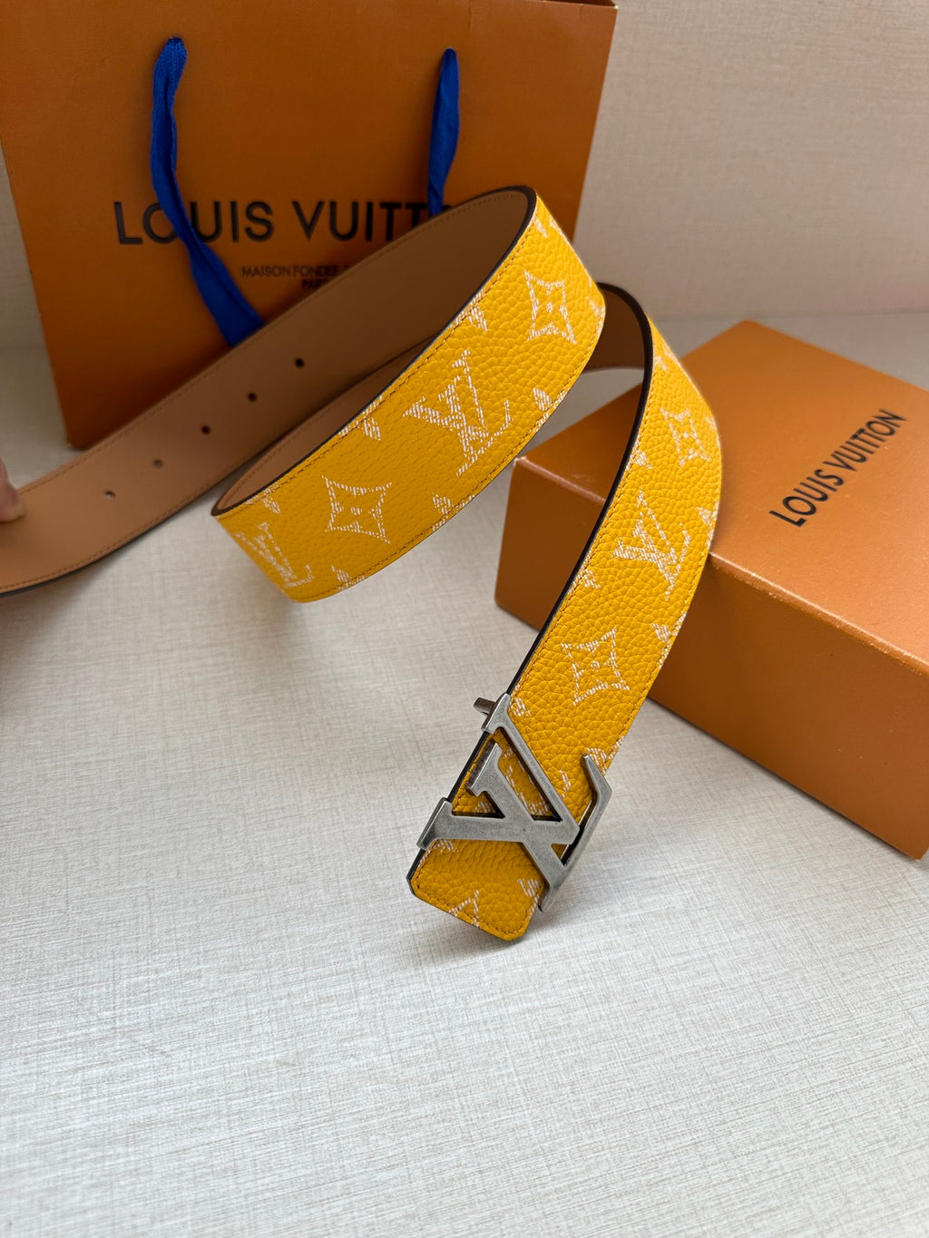 Yellow monogram leather belt with silver buckle, end shows punched holes
