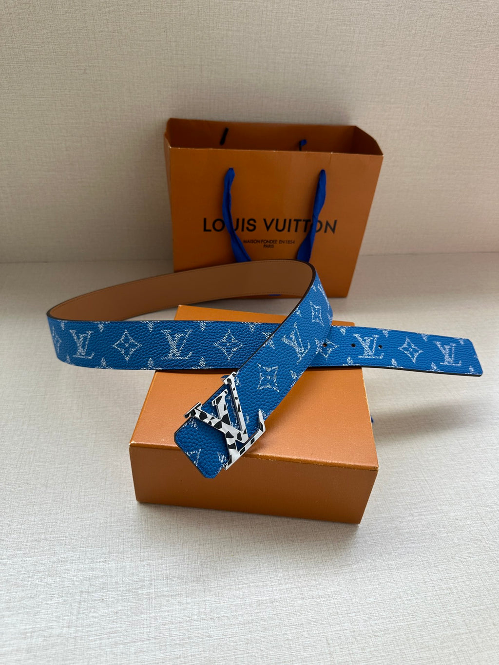 Louis Vuitton belt laid flat: blue monogram strap with gold-tone buckle hardware