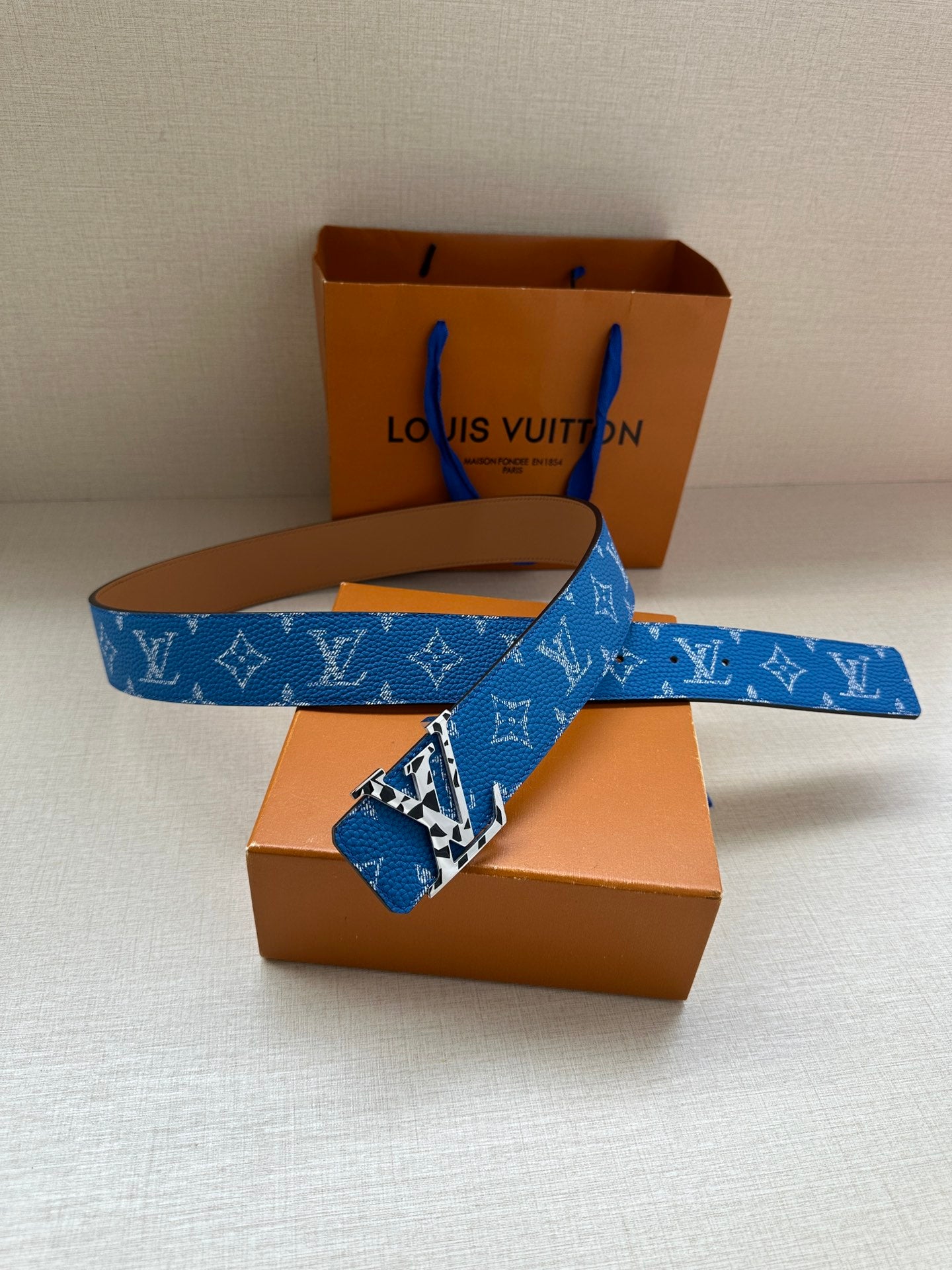 Louis Vuitton belt laid flat: blue monogram strap with gold-tone buckle hardware