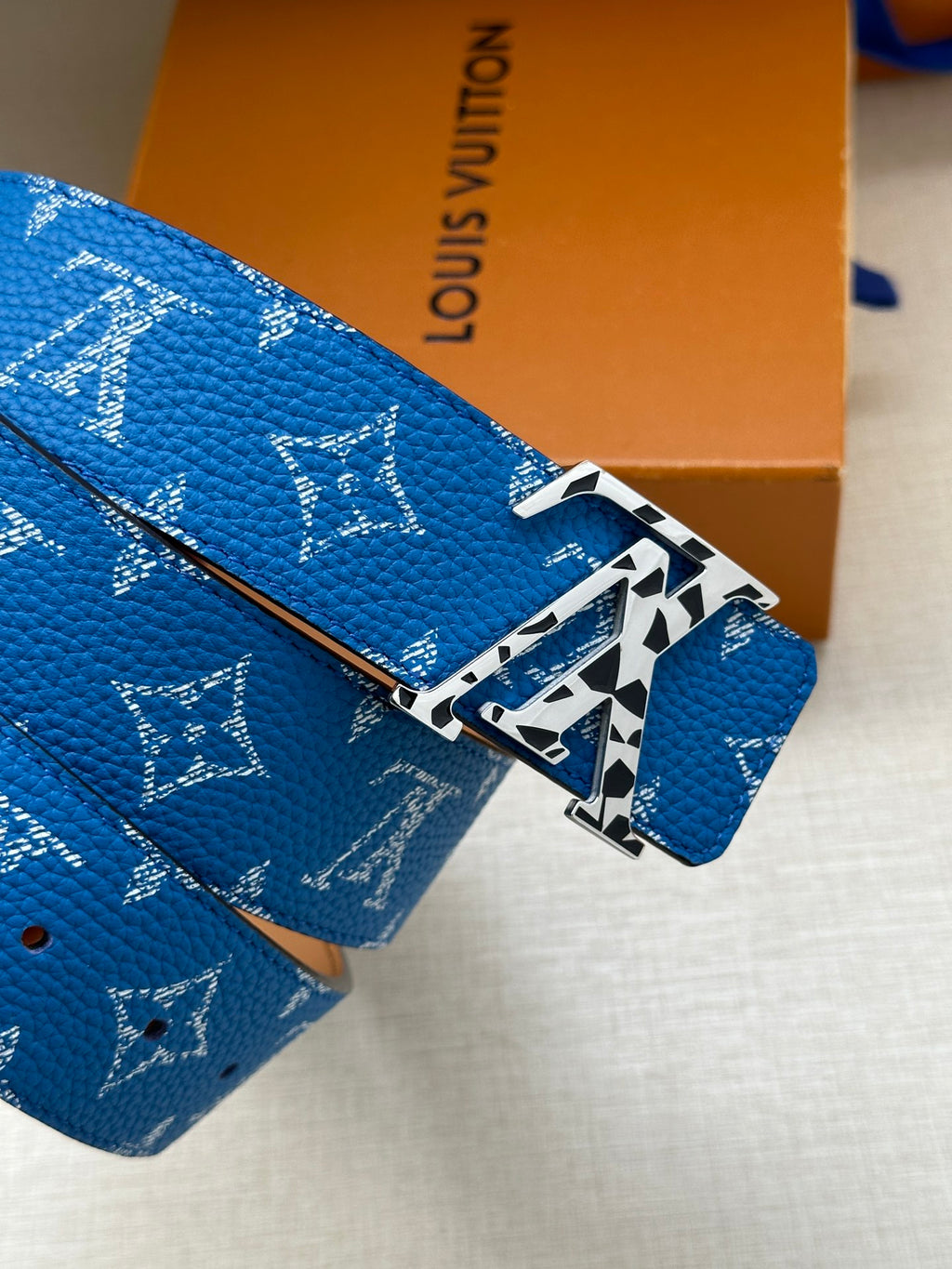 Louis Vuitton belt close-up: textured blue monogram strap with gold-tone buckle
