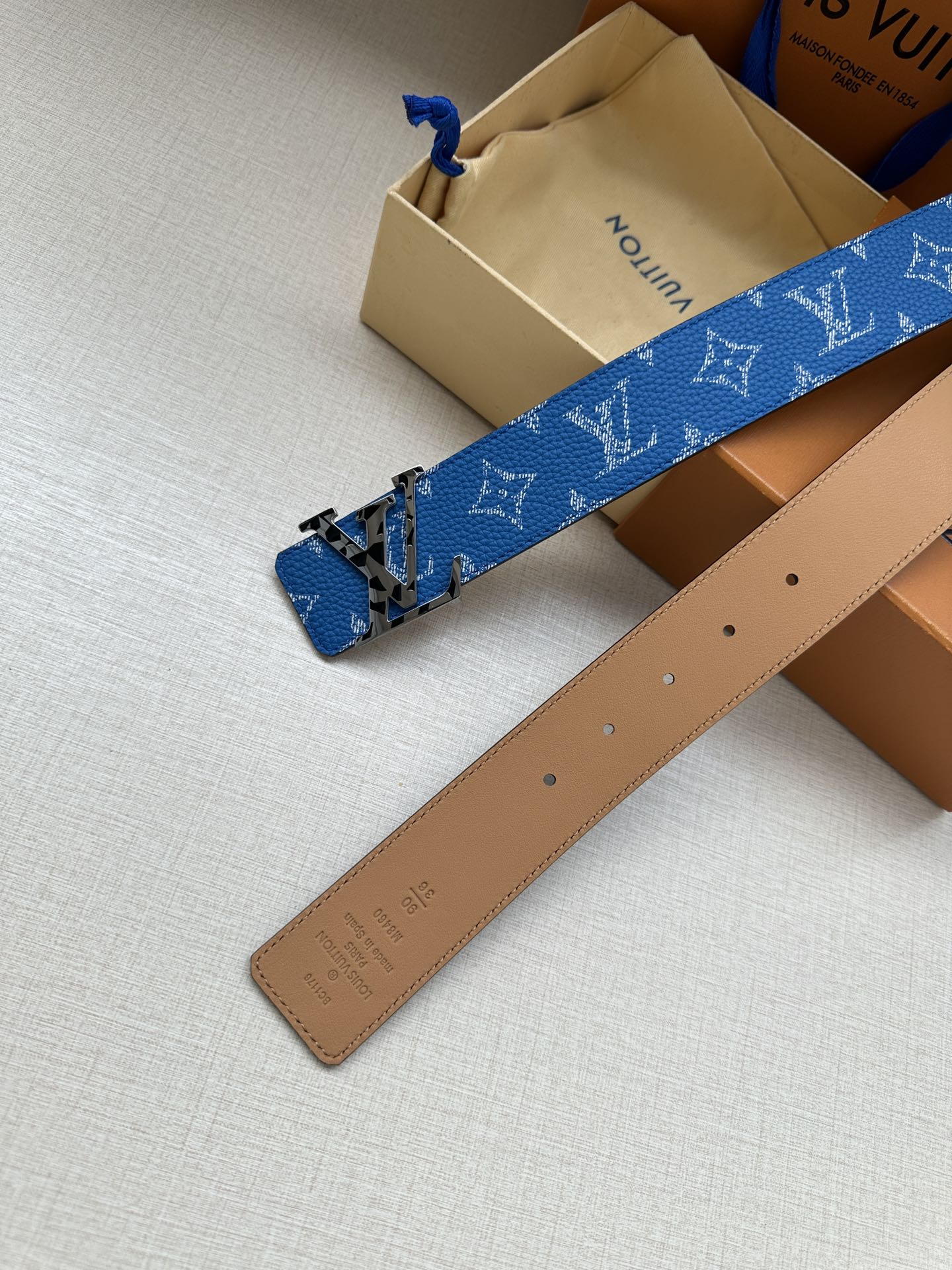 Louis Vuitton belt with blue monogram strap and tan leather back, gold buckle