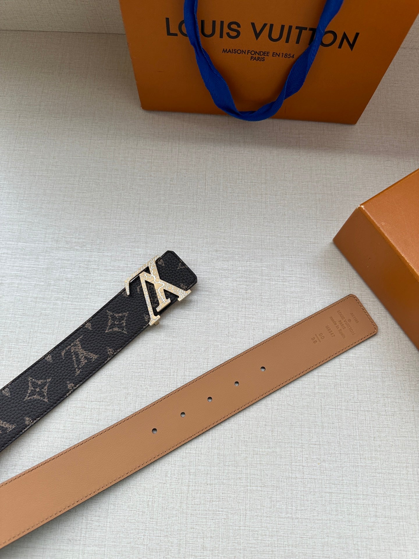 Louis Vuitton monogram belt with tan leather strap, punched holes, and gold-tone buckle