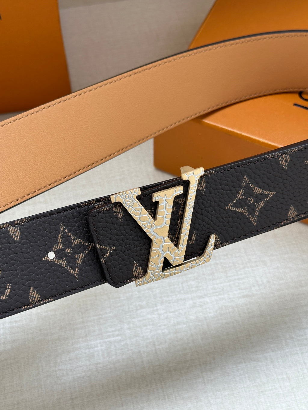 Louis Vuitton monogram belt close-up with gold buckle and dark patterned leather strap