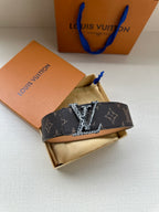 Louis Vuitton monogram belt with dark patterned strap and gold-tone buckle on box insert