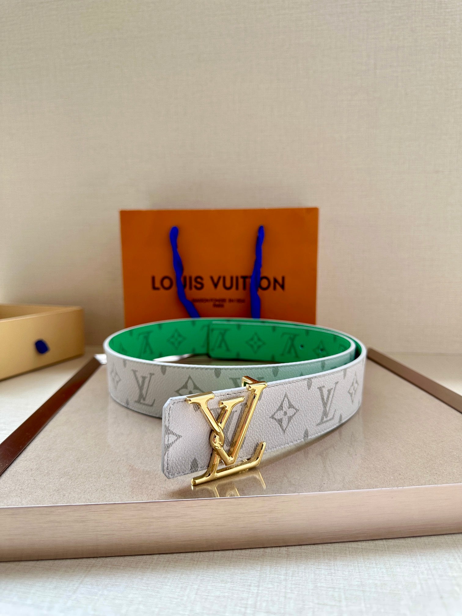 Louis Vuitton monogram belt in white with green lining and gold LV buckle, front view.