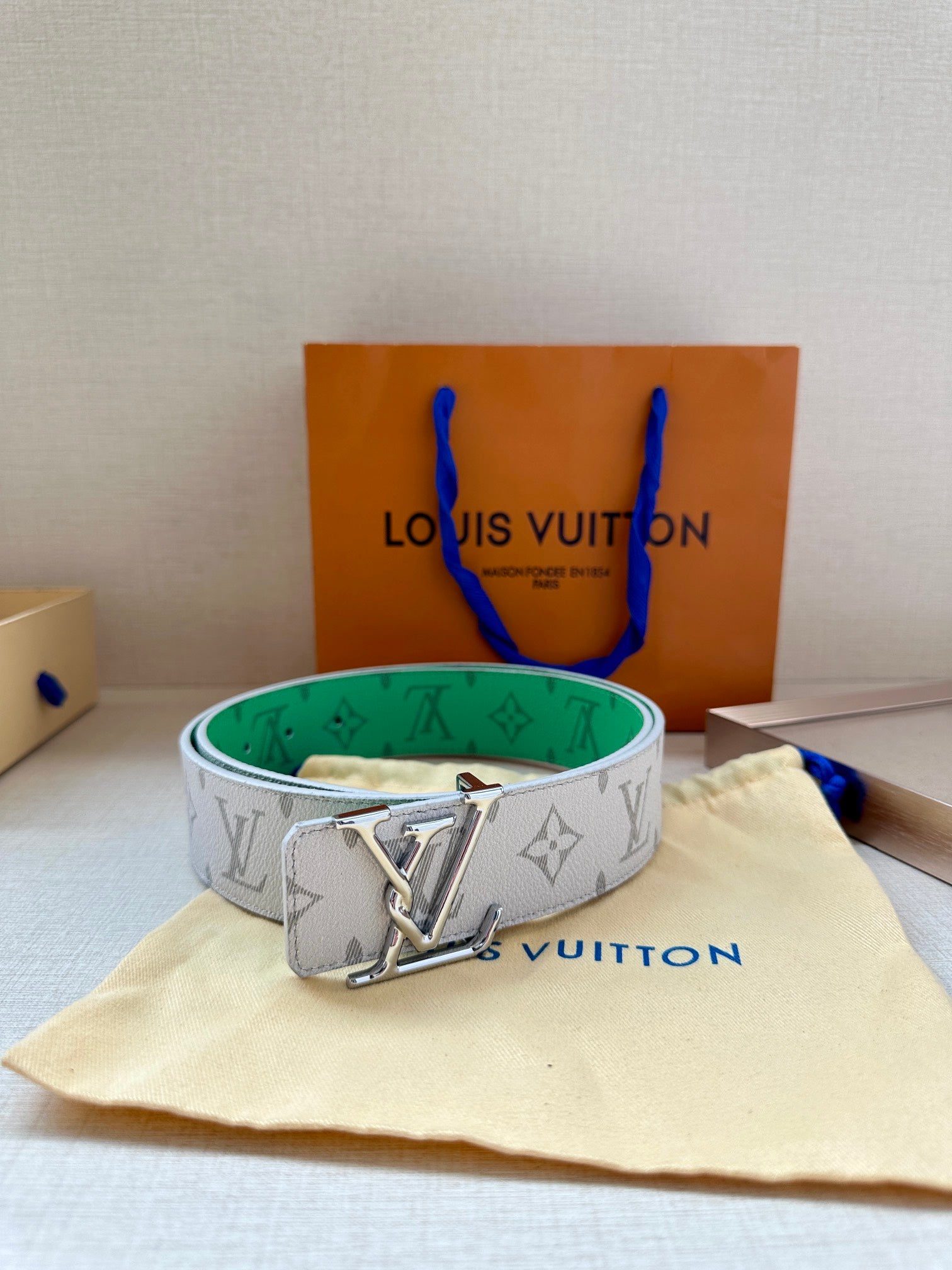 Louis Vuitton monogram belt in white with green lining and silver LV buckle, centered.