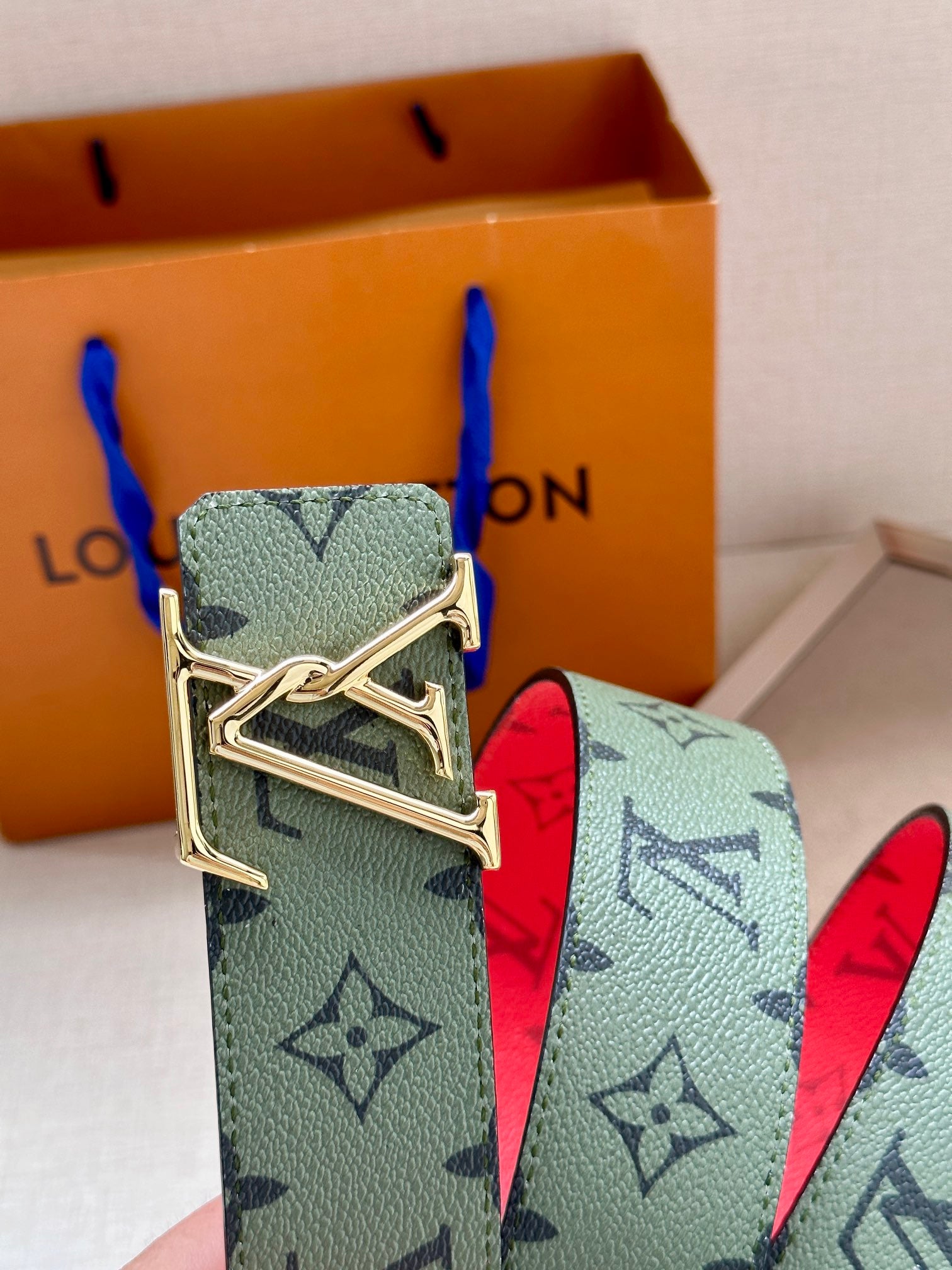 Louis Vuitton belt with mint monogram strap, red underside, and gold-tone buckle