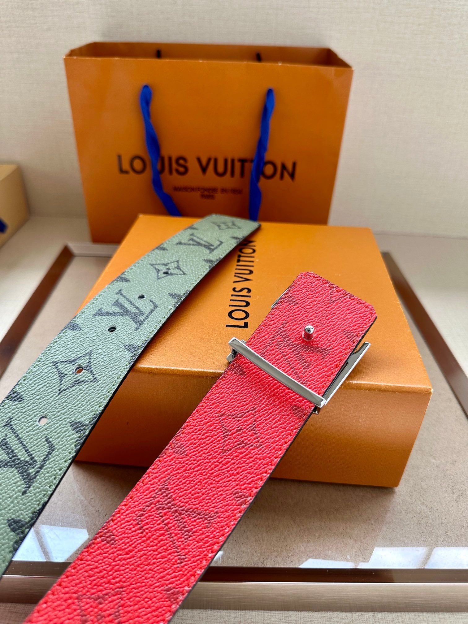 Louis Vuitton belt with textured red strap and silver-tone buckle on box tray