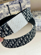 Dior belt close-up showing textured black and white logo pattern and silver center panel
