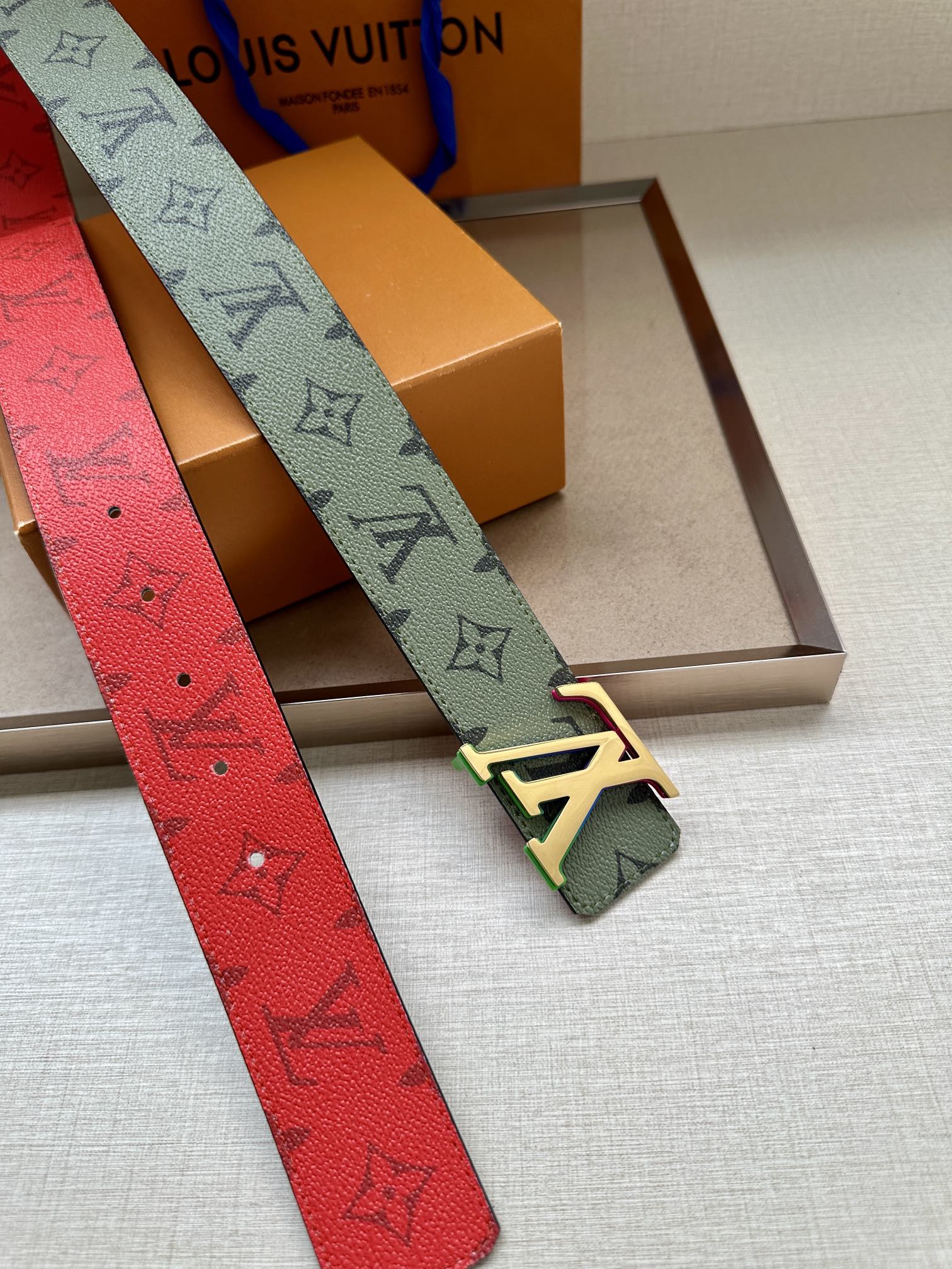 Louis Vuitton monogram belt with light green strap, multicolor buckle, red strap